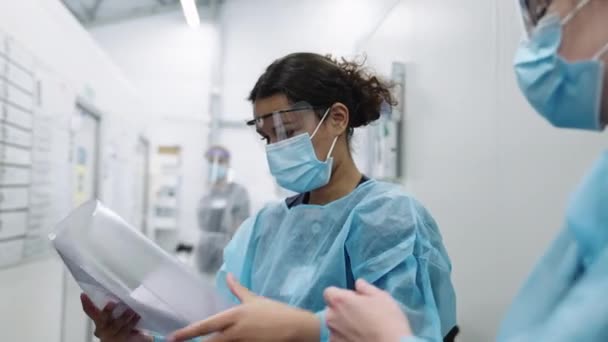 Ärzte mit Gesichtsmasken prüfen Papierkram — Stockvideo