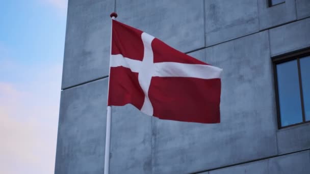 Bandera danesa soplando en el viento fuera del edificio — Vídeos de Stock