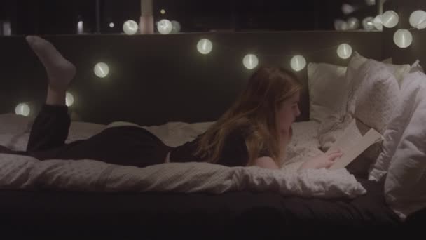 Teenage Girl Relaxing On Bed Reading Book — Stock videók