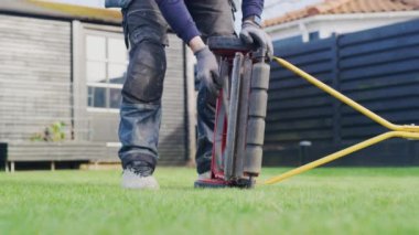 Çim biçme makinesini çim biçme makinesinde test eden adam.