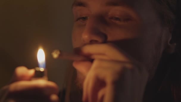 Человек, принимающий наркотики, зажигая косяк и вдыхая его — стоковое видео