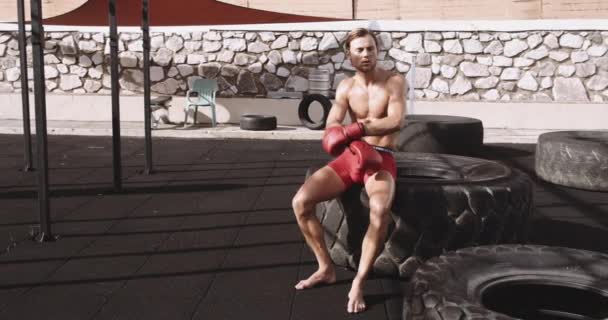 Young Boxer In Red Shorts Sitting On Tire — Stockvideo