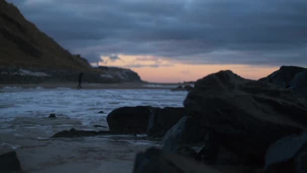 Personne marchant le long de la plage lorsque la marée arrive au coucher du soleil — Video