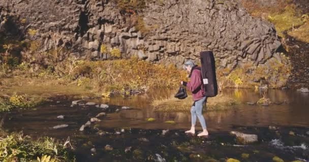 Caminhante jovem pisando sobre as rochas do rio — Vídeo de Stock