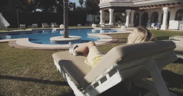 女子在后花园旁的游泳池边晒日光浴 — 图库视频影像
