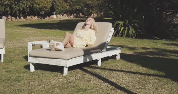 Mujer tomando el sol en la tarde con césped verde en el patio trasero — Vídeo de stock