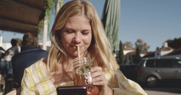 Sarışın Kadın, dışarıdaki bir restoranda Smoothie içiyor. — Stok video