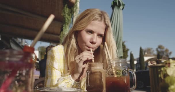 Kobieta Student siedzi przy stołach na świeżym powietrzu, próbując orzeźwiającego drinka — Wideo stockowe