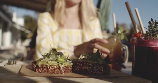 Zaostřený snímek Sezame-plněné chléb s guacamole se ženou v pozadí — Stock video