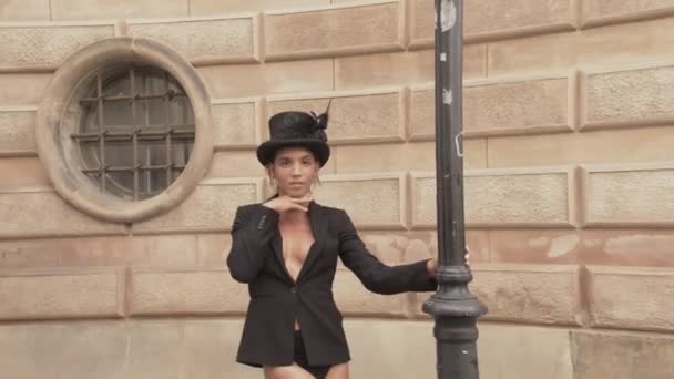 Танцовщица в верхней шляпе и куртке смотрит в камеру — стоковое видео
