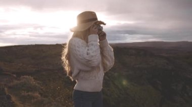 Gün batımında klasik kamera kullanan kadın.