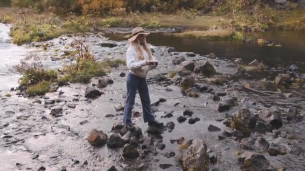 Junge Frau fotografiert mit Kamera von Felsen im Fluss — Stockvideo