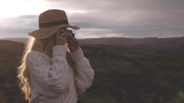 Blond vrouw met behulp van vintage camera in zonsondergang — Stockvideo