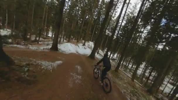 骑自行车疾驰而过冬季森林的无人机 — 图库视频影像