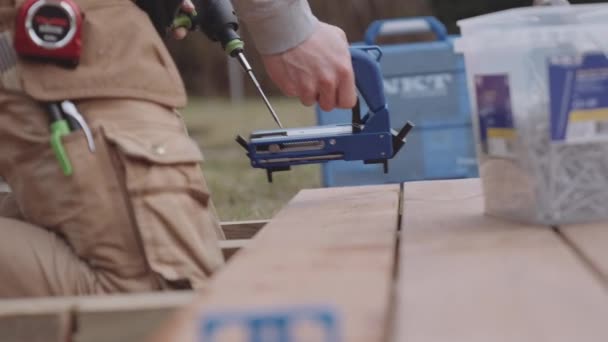 Carpintero poniendo tornillos en el Decking de madera — Vídeo de stock