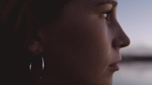 Mujer mirando lejos sobre el agua al atardecer — Vídeo de stock