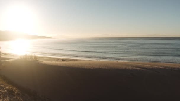 Frau spaziert im grellen Sonnenlicht über Meer und Sandstrand — Stockvideo