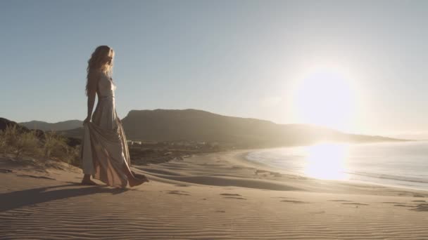 Mulher loira em fluxo vestido andando na praia — Vídeo de Stock