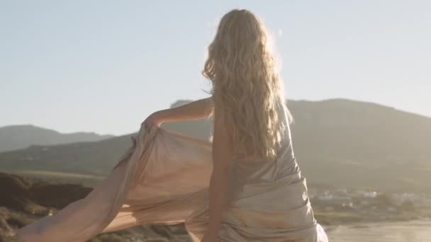 Женщина танцует в ярком солнечном свете на пляже — стоковое видео