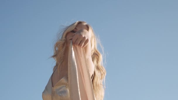 Жінка танцює в золотій сукні під блакитним небом — стокове відео