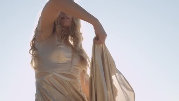 Mujer rubia bailando en vestido de oro al sol — Vídeo de stock