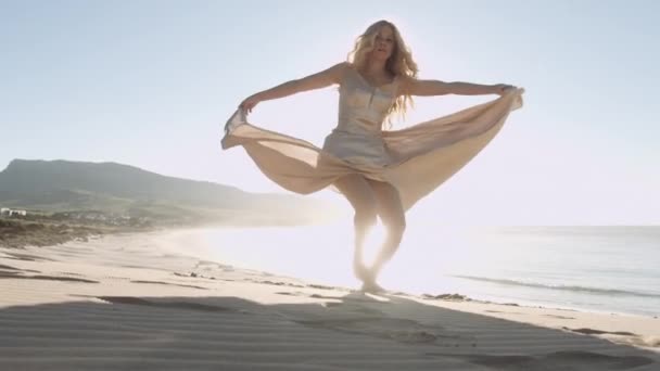 Bella donna bionda in abito d'oro sulla spiaggia esposta al sole — Video Stock