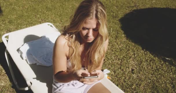 Donna bionda che scrive su smartphone nel giardino soleggiato — Video Stock