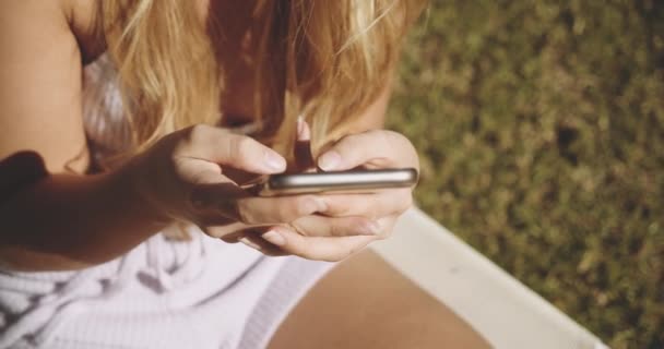 Ξανθιά γυναίκα γραπτών μηνυμάτων στο Smartphone στο Sunny Garden — Αρχείο Βίντεο