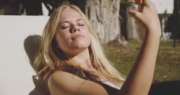 Женщина закрывает глаза, чтобы распылить солнцезащитный крем на лицо — стоковое видео