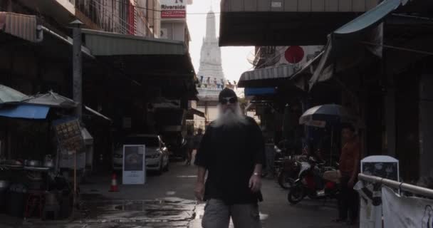 Male Expat in Thailand Walking Towards Camera Along Narrow Alley and Wat Arun Temple in Background — Stock Video