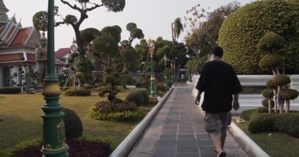 Mężczyzna Turysta w czarnej koszuli przy ścieżce ogród zbliża Wat Arun Temple Wejście — Wideo stockowe