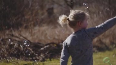 Tarlada Baloncuklarla Dönen Çocuk