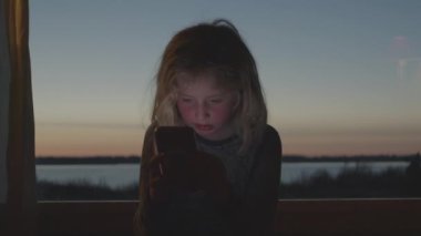 Genç çocuk Dusk 'ta akıllı telefonda oynuyor.