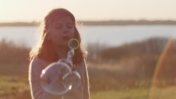 Giovane ragazza soffiando bolle attraverso bacchetta in tramonto — Video Stock