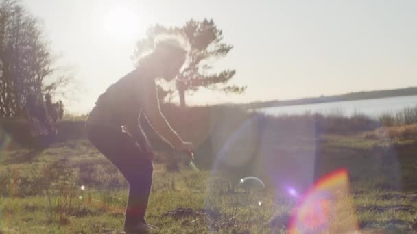 Ragazzo in piedi in sole campo e soffiando bolle — Video Stock