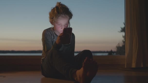 Mladý podle soustředění na Smartphone v soumraku — Stock video