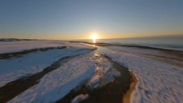 해 가 뜨는 사이에 있는 해안 과 호수 사이에 있는 눈덮인 바닥의 무늬 — 비디오