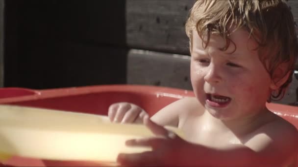 Pequeño niño jugando con juguetes en baño al aire libre — Vídeo de stock