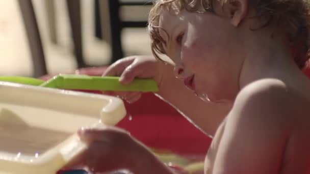 Menino brincando com água e brinquedos no banho ao ar livre — Vídeo de Stock