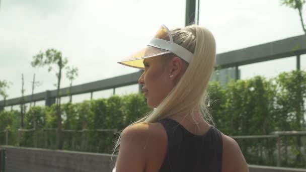 Blonde Tennisspielerin im hohen Pferdeschwanz, die zur Seite schaut — Stockvideo