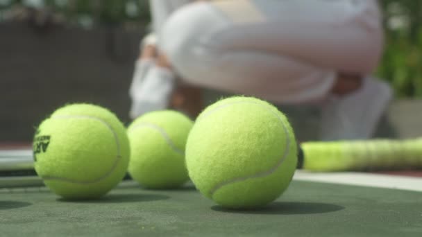 Balles de tennis et raquette sur le terrain de la Cour avec vue sur la femme — Video