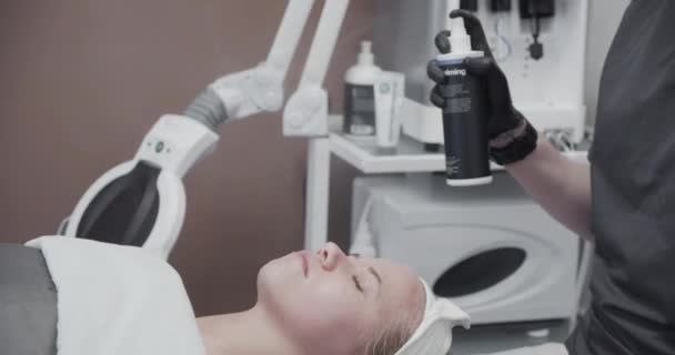 Kosmetyk rozpylanie produktu na twarz kobiety w salonie — Wideo stockowe