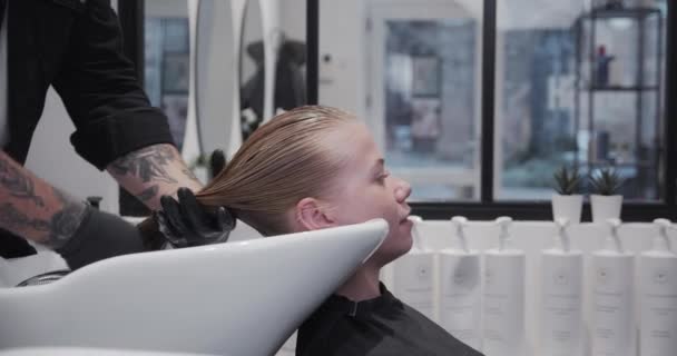 Парикмахер расчесывая волосы продукт в влажные волосы женщины — стоковое видео