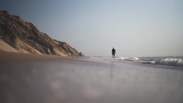 Man vandrar längs stranden som tidvattnet kommer in — Stockvideo