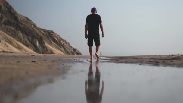 Άνθρωπος περπατώντας ξυπόλητος μέσα από θαλασσινό νερό στην παραλία — Αρχείο Βίντεο