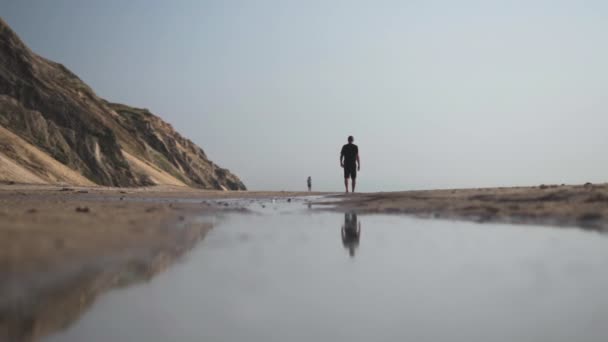 Man Walking Barefoot Through Seawater On Beach — стокове відео