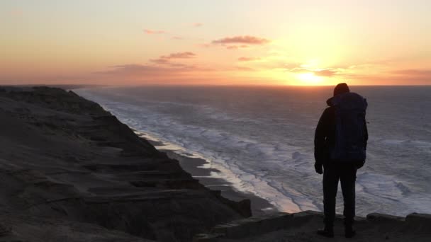 Caminhante assistindo pôr do sol sobre o mar — Vídeo de Stock