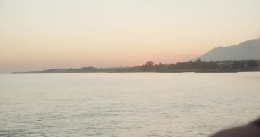 Deniz ve Kıyı Üzerinde Gün Batımını İzleyen Kadın