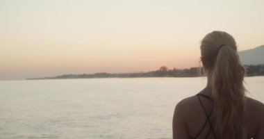 Sporcu Deniz Üzerinde Gün Batımını ve Kıyı şeridini İzliyor