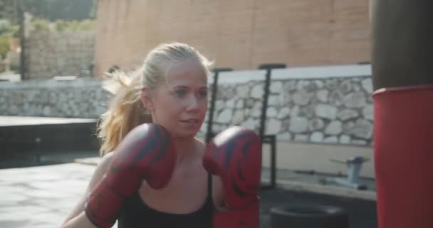 Woman Punching Bag In Boxing Gloves At Outdoor Gym — Vídeo de Stock